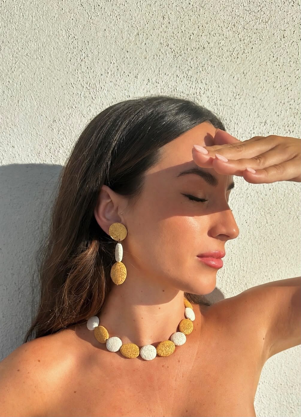 Collar y pendientes CALIA blanco y ocre, con la mano en la frente